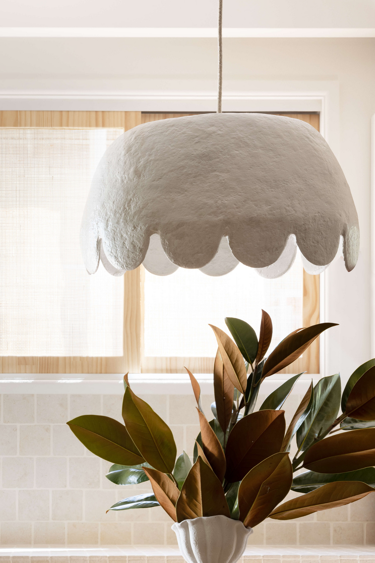 White oversize pendant light with scalloped edge hanging in a kitchen