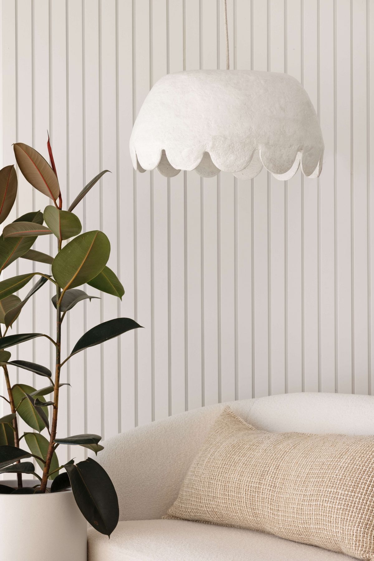 Oversize pendant light with scalloped edge hanging above a sofa