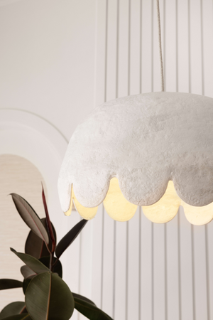 Close up of white oversize pendant light with scalloped edge with light on