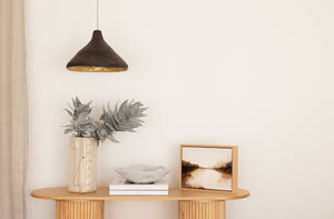 Charcoal sustainable pendant light hanging above a hallway console